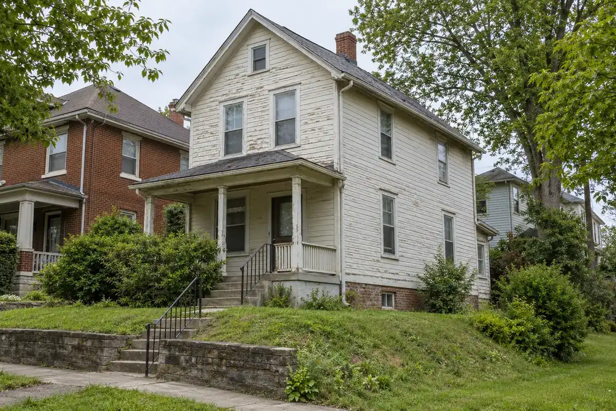 A house with peeling paint and worn roof shingles that needs repairs